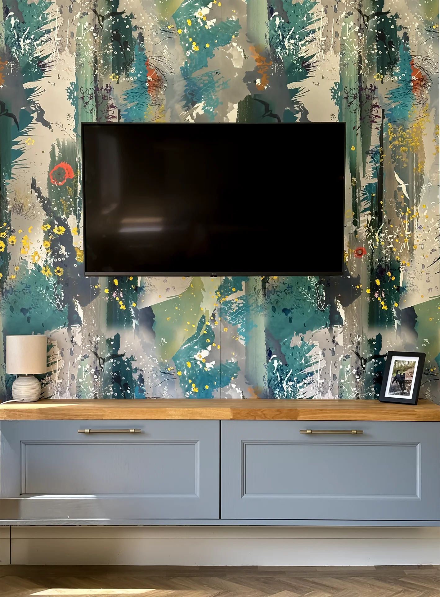 Wall-mounted TV with artistic wallpaper and wooden shelf